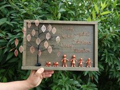 a person holding up a sign with small figurines on it in front of some trees