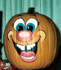 a pumpkin with an evil clown face painted on it's front and side, sitting next to candy