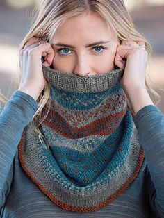 a woman wearing a knitted cowl with her hands on her face and covering her mouth