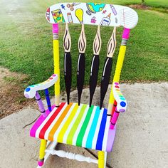 a multicolored wooden rocking chair sitting on top of a cement slab next to grass