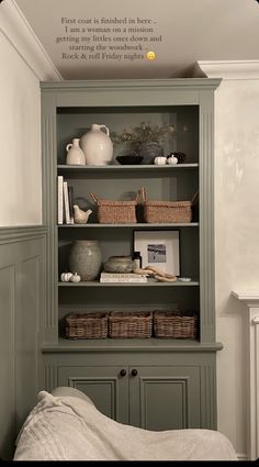 a green bookcase with baskets on top of it