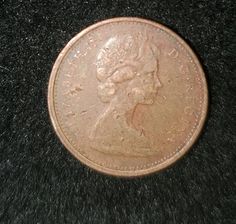 an old penny is laying on top of a black surface with the image of a woman's head