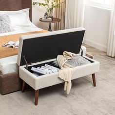 a bed with an ottoman underneath it and magazines on the bottom shelf next to it