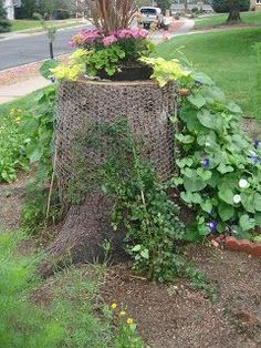 a potted planter sitting on top of a tree stump in the middle of a garden