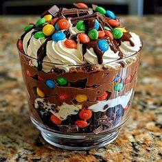 a dessert in a glass bowl on a counter with lots of candy and candies