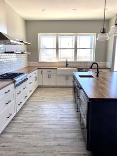 a large kitchen with white cabinets and wood counter tops, along with an island in the middle