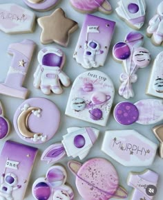 purple and white decorated cookies are arranged on a table