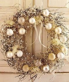 a wreath with white and gold ornaments hanging on the front door, ready to be decorated for christmas