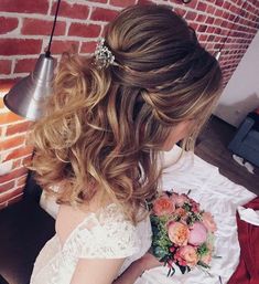 a woman in a white dress holding a bouquet of flowers next to a brick wall