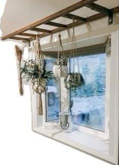 two vases with plants are hanging in front of a window that is partially open