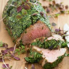 a piece of meat covered in herbs on a cutting board