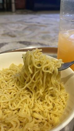 a spoon full of noodles and orange juice