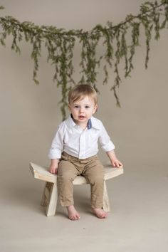 a little boy sitting on top of a wooden bench