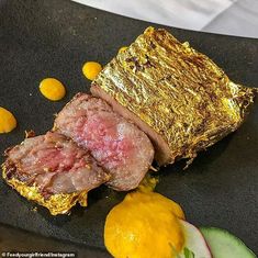 some food is laying out on a black plate with yellow and green vegetables around it