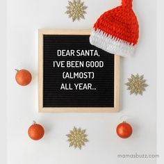 a santa hat on top of a black board next to christmas ornaments and snowflakes