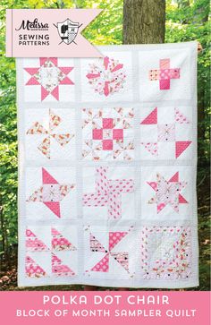 a pink and white quilt hanging from a tree