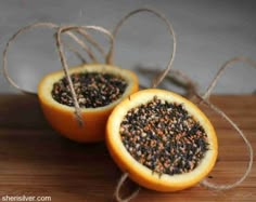 two halves of an orange with seeds in it sitting on a wooden table next to twine strings