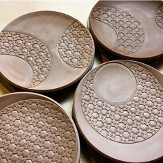 four brown plates sitting on top of a table next to each other with designs on them