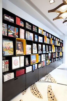 a book shelf filled with lots of books on top of a white floor next to a wall