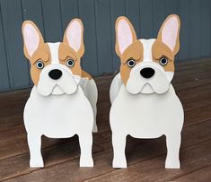 two paper cut out dogs sitting on top of a wooden floor next to each other