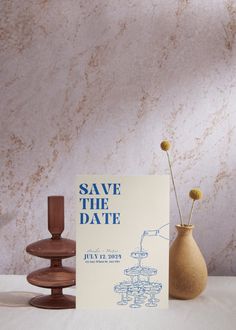 a save the date card sitting on top of a table next to two vases