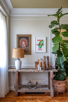 a room with a table, potted plant and pictures on the wall