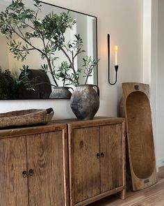 a wooden cabinet with two vases on top and a mirror in the corner behind it