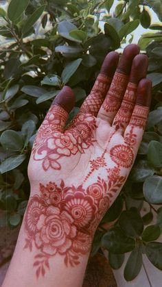 a hand with henna on it next to some plants