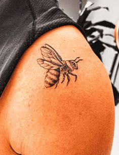 the back of a woman's thigh with a tattoo of a bee on it