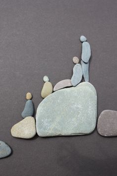 several small rocks arranged in the shape of people standing on top of one another and holding hands