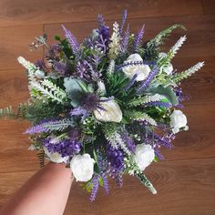 a bouquet of flowers is being held by someone's hand on a wooden floor