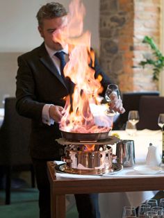 a man standing in front of a pot on top of a table filled with wine glasses