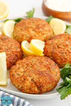 three crab cakes on a plate with lemons and parsley next to the plate