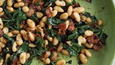 a green plate topped with beans and spinach