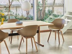 a dining room table with four chairs and a vase on the table next to it