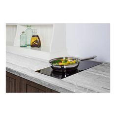 a bowl of food sitting on top of a stove next to an oven hood and counter