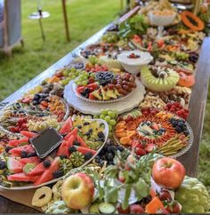 a long table filled with lots of different types of fruits and veggies on plates