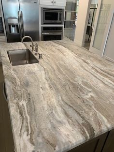 a kitchen with marble counter tops and stainless steel appliances in the backround area