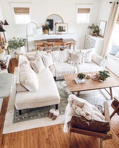 a living room filled with white furniture and lots of pillows on top of it's couch