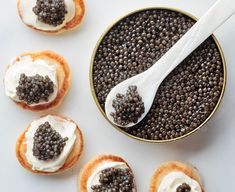 several small pastries with white frosting and black cavias in a bowl