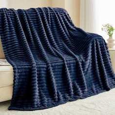 a large blue blanket sitting on top of a couch next to a white window sill