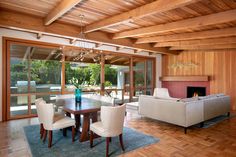 a dining room table with chairs and a couch in front of a fire place that is built into the wall