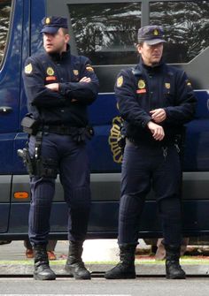 two police officers are standing in front of a blue van with their arms crossed and looking at something