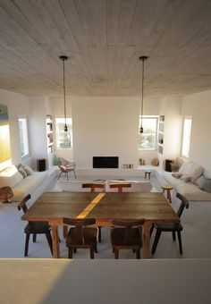 an open concept living room and dining area with white walls, wood flooring and modern furniture