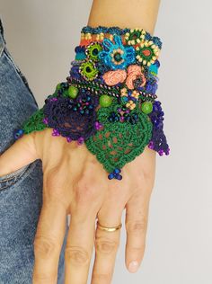 a woman's hand is adorned with colorful beads and crocheted bracelets