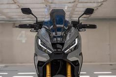 the front end of a silver motorcycle parked in a parking garage with no one around