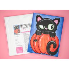 a black cat sitting on top of a pumpkin next to an envelope with the letter c