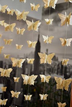 paper butterflies hanging from strings in front of a cityscape with buildings and skyscrapers