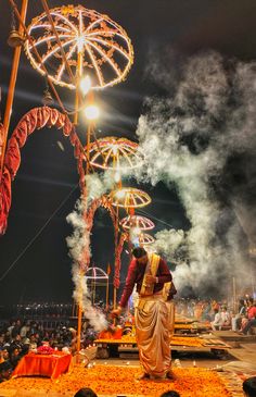 a man standing on top of a stage next to a giant firework structure at night