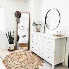 a bedroom with a white dresser, mirror and rug on the floor in front of it